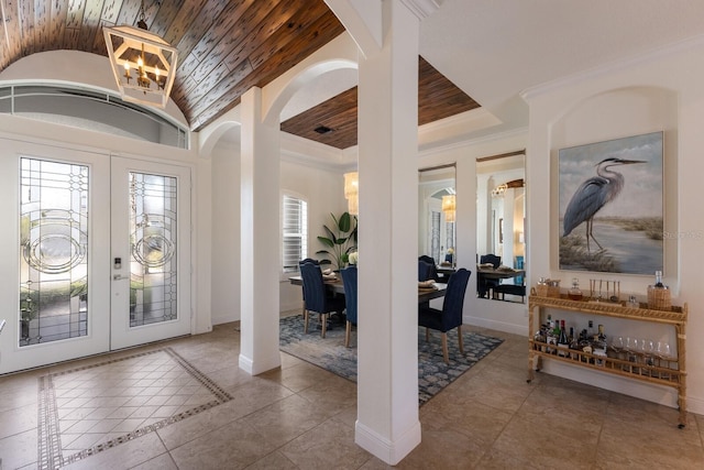 tiled entrance foyer with crown molding, lofted ceiling, wood ceiling, and french doors