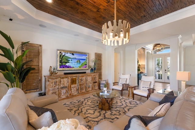 living room featuring french doors, crown molding, wooden ceiling, a tray ceiling, and a notable chandelier