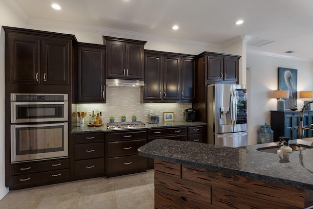 kitchen featuring dark brown cabinetry, stainless steel appliances, decorative backsplash, and dark stone counters