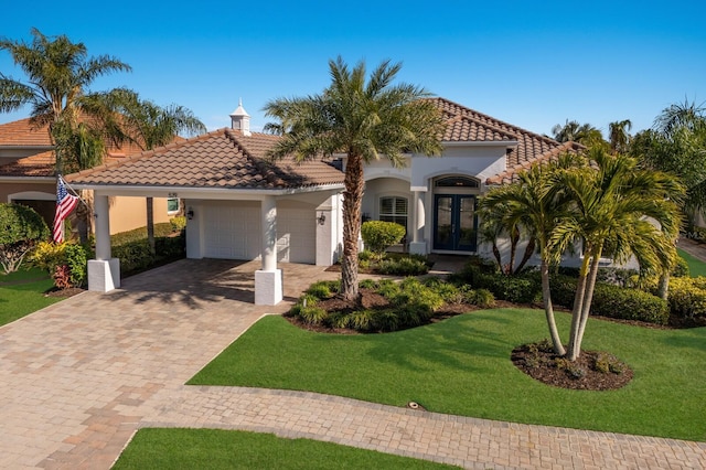 mediterranean / spanish-style home featuring a garage, a front lawn, and french doors