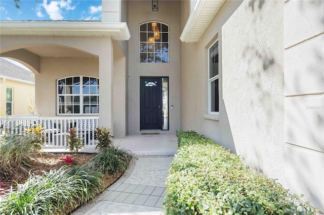 entrance to property featuring stucco siding and covered porch