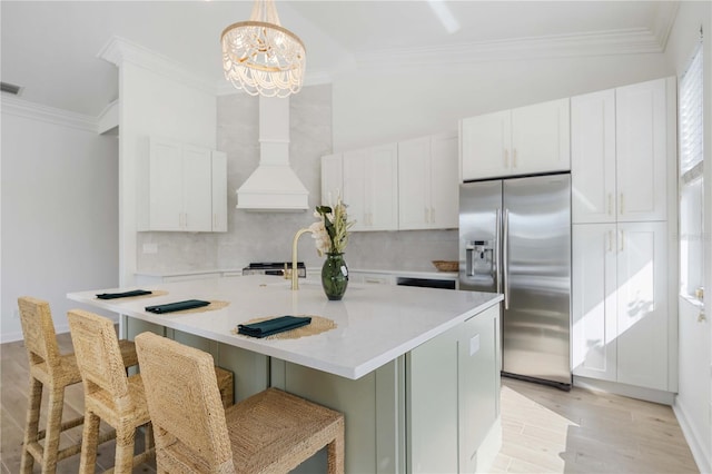 kitchen with backsplash, crown molding, light wood-style flooring, white cabinets, and stainless steel fridge