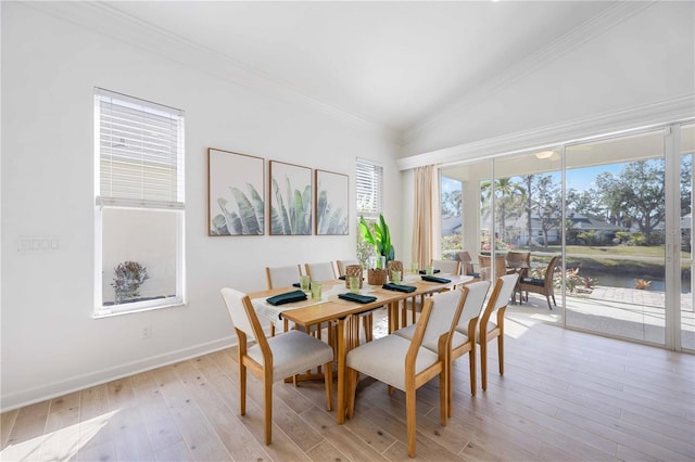 dining space with baseboards, light wood finished floors, crown molding, and vaulted ceiling