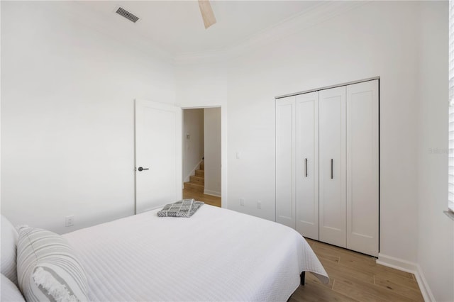 bedroom featuring crown molding, a closet, ceiling fan, and light hardwood / wood-style flooring