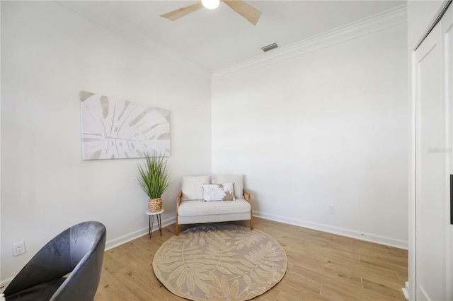 sitting room with ceiling fan, light wood-style flooring, baseboards, and ornamental molding