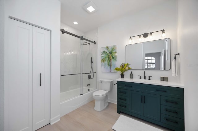 bathroom with vanity, toilet, wood finished floors, and combined bath / shower with glass door