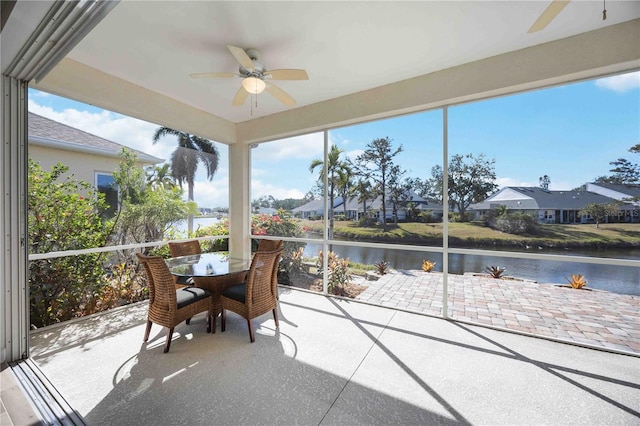 sunroom / solarium featuring a water view, a residential view, and ceiling fan