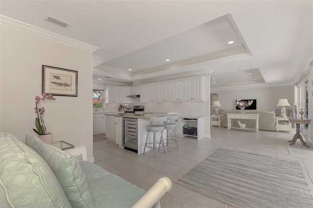 tiled living room featuring ornamental molding, a raised ceiling, and beverage cooler