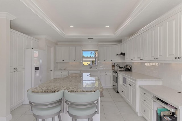 kitchen featuring stainless steel range with electric stovetop, a tray ceiling, and white cabinetry