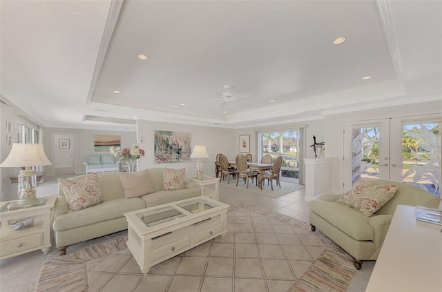 tiled living room featuring french doors, ornamental molding, and a tray ceiling