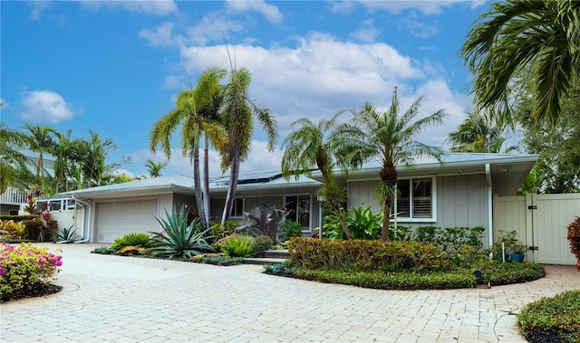 single story home with a garage and solar panels