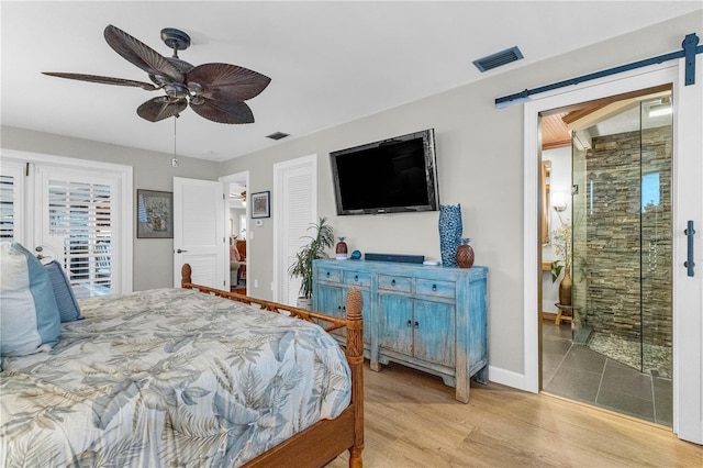 bedroom with ceiling fan, a barn door, light hardwood / wood-style floors, and access to exterior