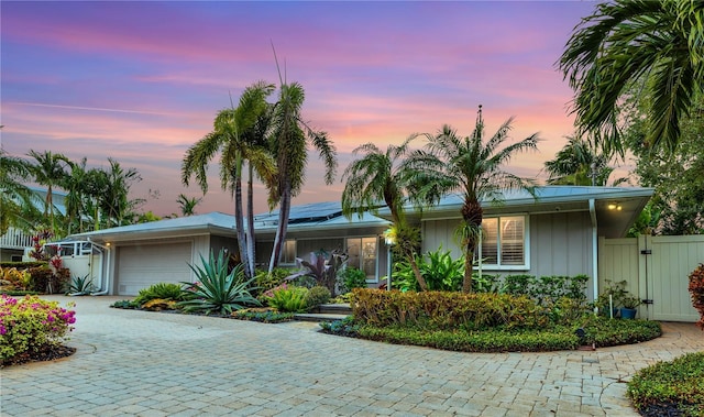 ranch-style home with a garage and solar panels