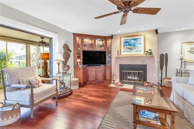 living area featuring ceiling fan, a premium fireplace, and wood finished floors