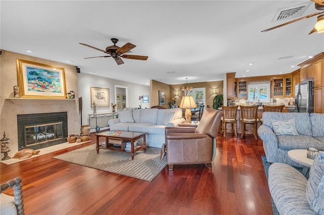 living area featuring visible vents, dark wood-style flooring, a high end fireplace, and a ceiling fan