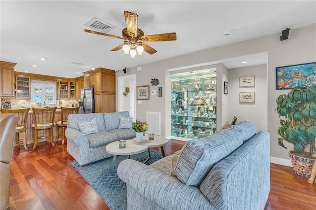 living room featuring baseboards, visible vents, ceiling fan, and wood finished floors