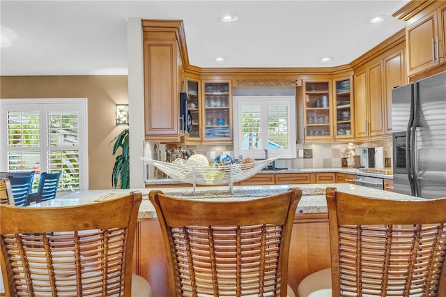 kitchen with light countertops, stainless steel refrigerator with ice dispenser, backsplash, and a healthy amount of sunlight