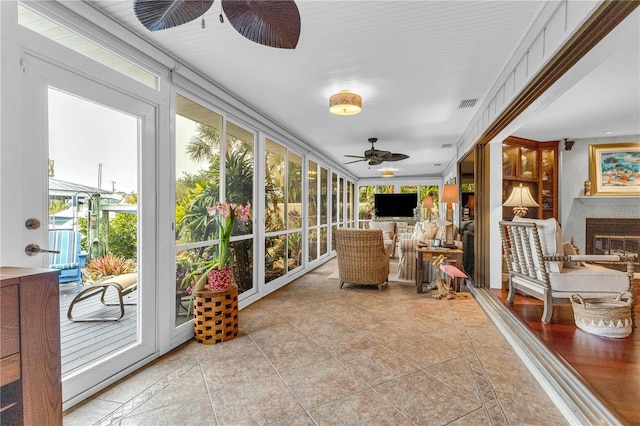 sunroom / solarium featuring ceiling fan, a fireplace, and visible vents