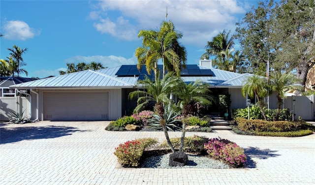 view of front of property featuring metal roof, a garage, fence, decorative driveway, and a gate