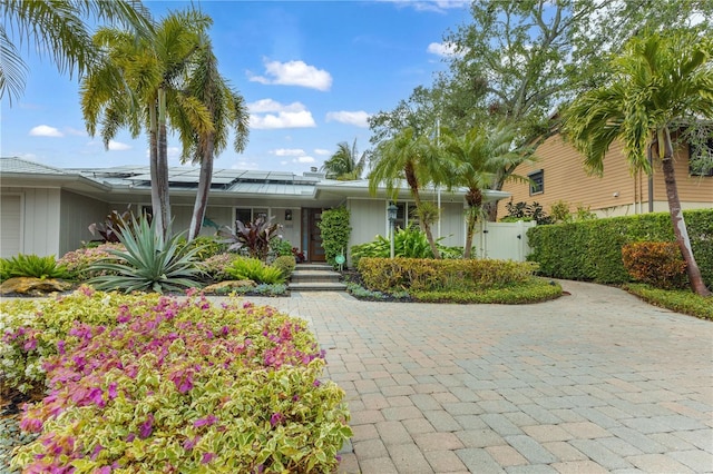 view of front of home with roof mounted solar panels, fence, an attached garage, and a gate