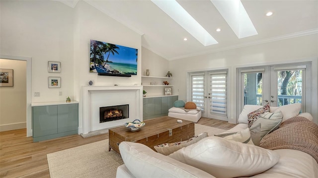 living room with french doors, a skylight, high vaulted ceiling, light hardwood / wood-style flooring, and ornamental molding