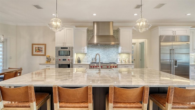 kitchen featuring a spacious island, appliances with stainless steel finishes, white cabinets, and wall chimney exhaust hood