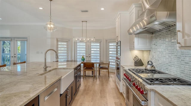 kitchen featuring white cabinets, hanging light fixtures, exhaust hood, light stone counters, and french doors