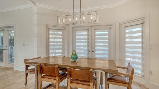 dining room with crown molding, an inviting chandelier, light hardwood / wood-style floors, and french doors