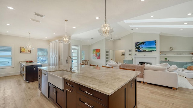 kitchen with sink, light hardwood / wood-style flooring, an island with sink, and vaulted ceiling