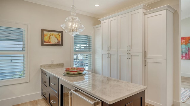 kitchen featuring light stone counters, light wood-type flooring, ornamental molding, pendant lighting, and white cabinets