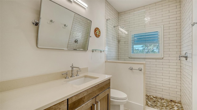 bathroom with vanity, tiled shower, and toilet