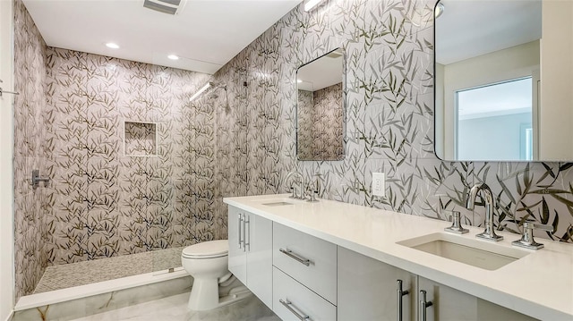 bathroom with a tile shower, vanity, and toilet