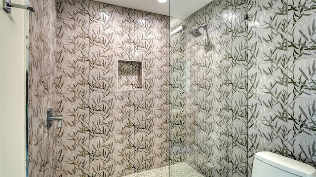 bathroom featuring a tile shower and toilet