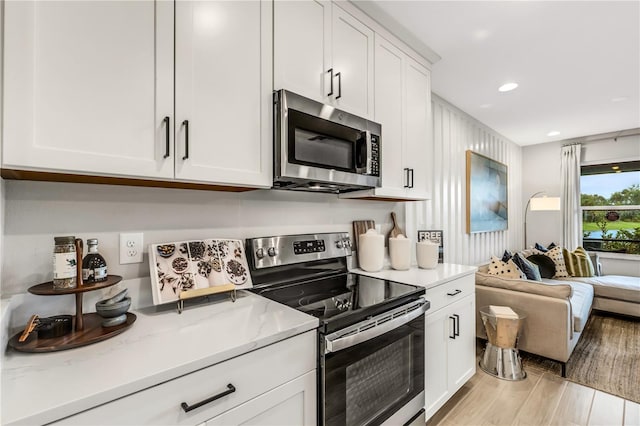 kitchen with stainless steel appliances, light stone countertops, and white cabinets