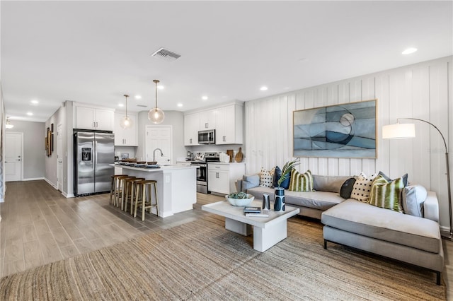 living room featuring sink and light hardwood / wood-style flooring