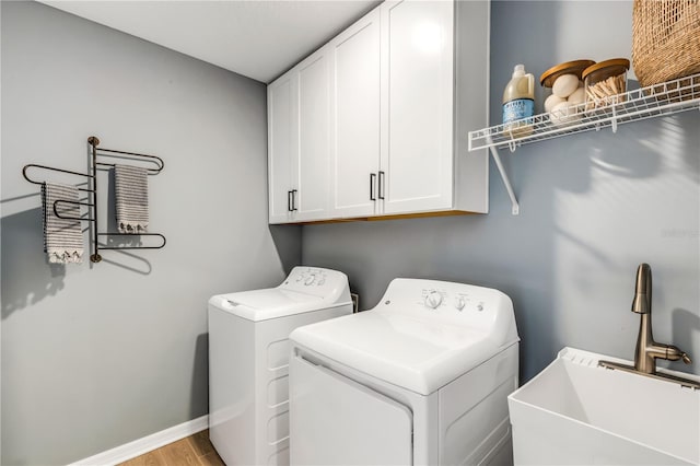 laundry room featuring cabinets, washer and dryer, sink, and light wood-type flooring