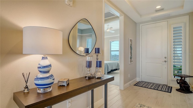 entryway with light hardwood / wood-style floors and a raised ceiling