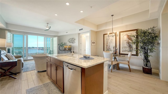 kitchen with sink, hanging light fixtures, a water view, a center island with sink, and stainless steel dishwasher