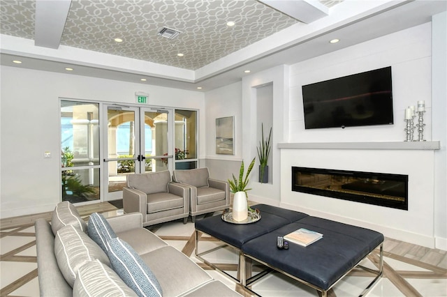 living room with a raised ceiling and french doors