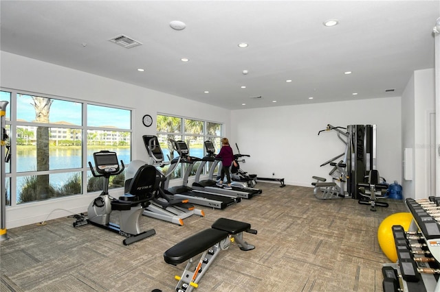 exercise room with carpet flooring and a water view