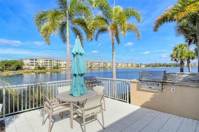 view of patio with a water view, an outdoor kitchen, and a grill