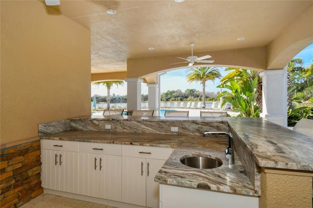 view of patio featuring sink, ceiling fan, and a water view