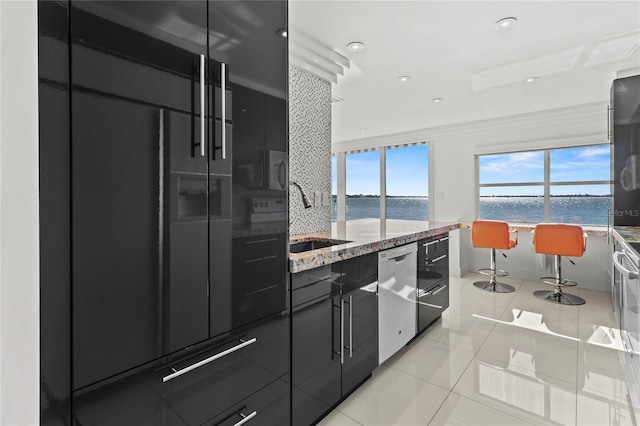 kitchen with a water view, dishwasher, sink, and light tile patterned floors