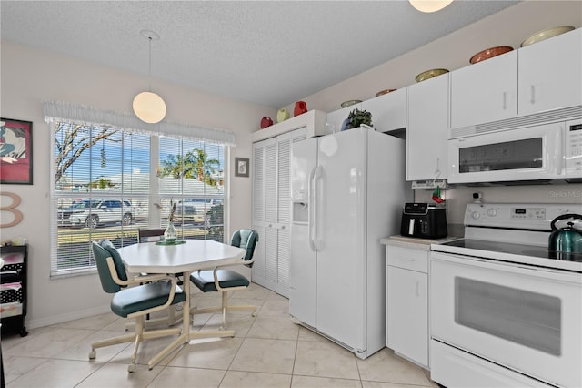 kitchen with pendant lighting, light tile patterned floors, white appliances, a textured ceiling, and white cabinets