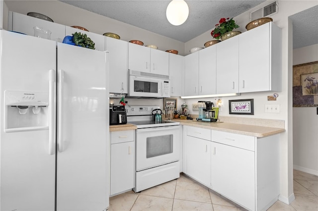 kitchen with white cabinets, light tile patterned floors, a textured ceiling, and white appliances