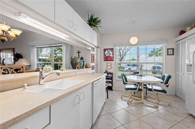 kitchen with pendant lighting, sink, white cabinets, white appliances, and a textured ceiling