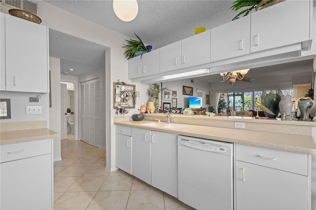 kitchen featuring sink, white cabinetry, a textured ceiling, light tile patterned floors, and dishwasher