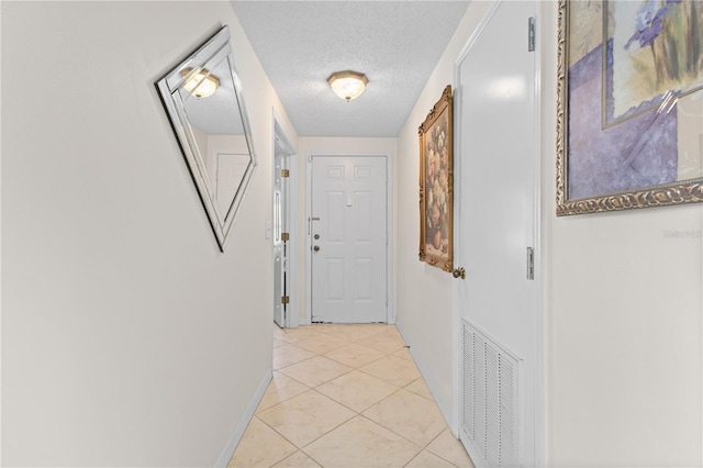 hallway featuring light tile patterned floors and a textured ceiling