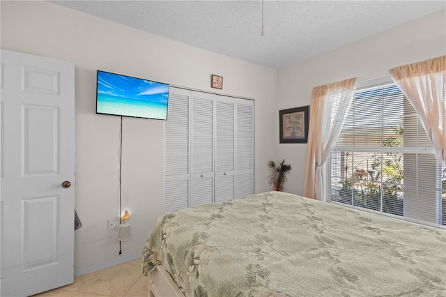 bedroom featuring light tile patterned floors, a textured ceiling, and a closet