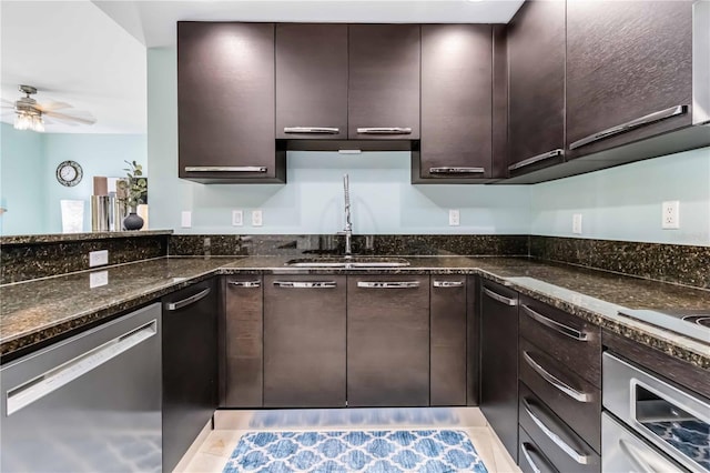 kitchen featuring dishwasher, sink, dark stone counters, ceiling fan, and dark brown cabinetry